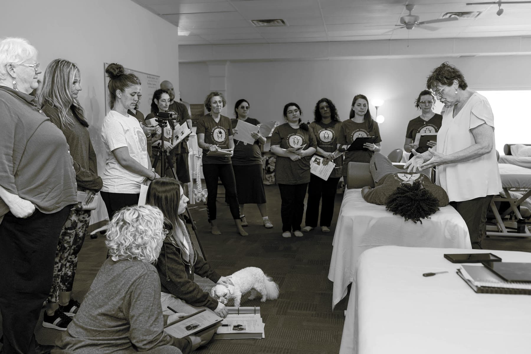 Leigh Ankrum demonstrating at the table while a room of practitioners observes